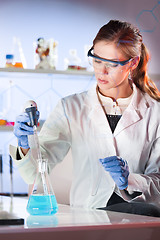 Image showing Young scientist pipetting in life science laboratory.