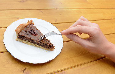 Image showing Woman cutting into a slice of pecan pie