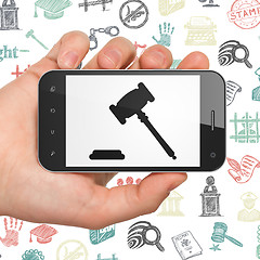 Image showing Law concept: Hand Holding Smartphone with Gavel on display