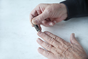 Image showing older man trims fingernails