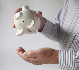 Image showing businessman emptying piggy bank