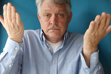 Image showing older man with his hands up