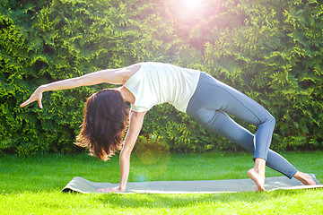 Image showing pretty adult woman doing yoga on a green grass