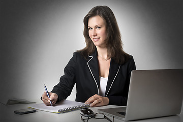Image showing Smiling businesswoman writing something