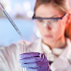 Image showing Young scientist pipetting in life science laboratory.