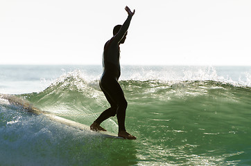 Image showing Long boarder surfing the waves at sunset