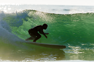 Image showing Long boarder surfing the waves at sunset