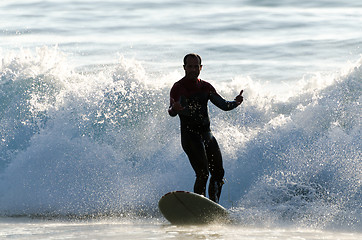 Image showing Long boarder surfing the waves at sunset