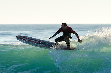 Image showing Long boarder surfing the waves at sunset