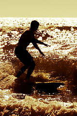 Image showing Longboarder surfing at sunset