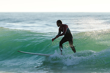 Image showing Long boarder surfing the waves at sunset