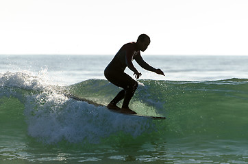 Image showing Long boarder surfing the waves at sunset