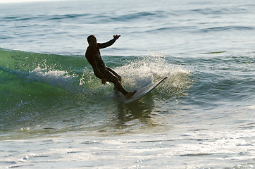 Image showing Long boarder surfing the waves at sunset