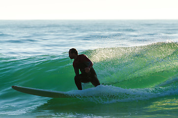 Image showing Long boarder surfing the waves at sunset