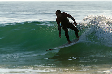 Image showing Long boarder surfing the waves at sunset