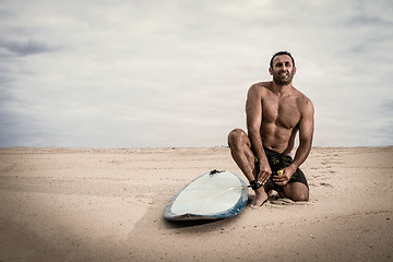 Image showing Surfer tying his surfboard\'s leach