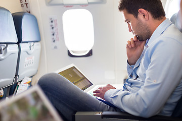 Image showing Businessman working with laptop on airplane.