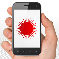 Image showing Tourism concept: Hand Holding Smartphone with Sun on display