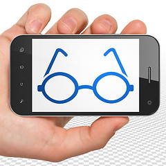 Image showing Studying concept: Hand Holding Smartphone with Glasses on display