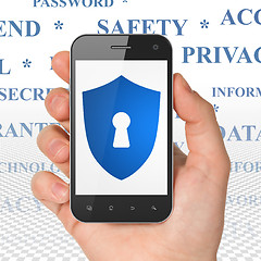 Image showing Protection concept: Hand Holding Smartphone with Shield With Keyhole on display