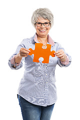 Image showing Elderly woman holding a puzzle piece