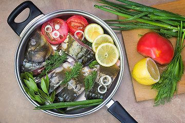 Image showing Fish and components for her preparation in a large skillet.