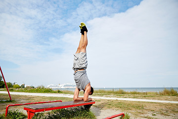 Image showing young man exercising on bench outdoors