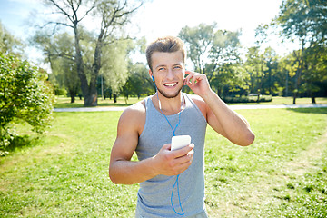 Image showing happy man with earphones and smartphone at park