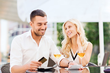 Image showing happy couple with bank card and bill at restaurant