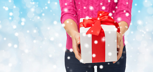 Image showing close up of woman in pink sweater holding gift box