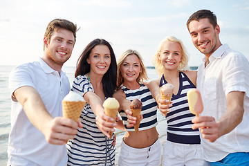 Image showing smiling friends eating ice cream on beach