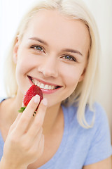 Image showing happy woman eating strawberry at home