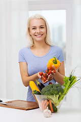 Image showing smiling young woman cooking vegetables at home