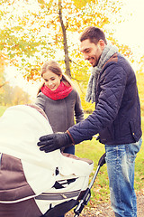 Image showing smiling couple with baby pram in autumn park