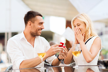 Image showing happy couple with engagement ring and wine at cafe