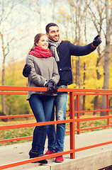 Image showing smiling couple hugging on bridge in autumn park