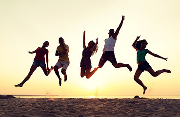 Image showing smiling friends dancing and jumping on beach