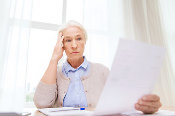 Image showing senior woman with papers and calculator at home