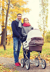 Image showing smiling couple with baby pram in autumn park