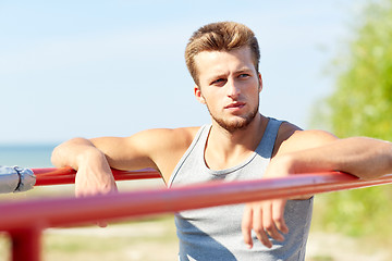 Image showing young man exercising on parallel bars outdoors