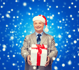 Image showing smiling man in suit and santa helper hat with gift