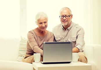 Image showing happy senior couple with laptop and cups at home