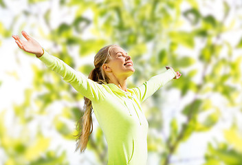 Image showing happy woman in sport clothes raising hands