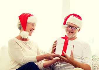 Image showing happy senior couple in santa hats with gift box