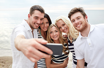 Image showing happy friends on beach and taking selfie