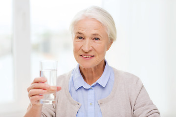 Image showing happy senior woman with glass of water at home