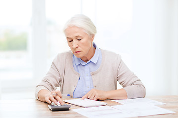 Image showing senior woman with papers and calculator at home