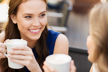 Image showing smiling young women with coffee cups at cafe