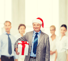 Image showing smiling man in suit and santa helper hat with gift