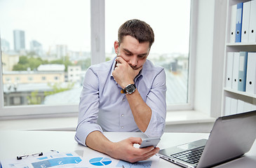 Image showing businessman with smartphone and laptop at office